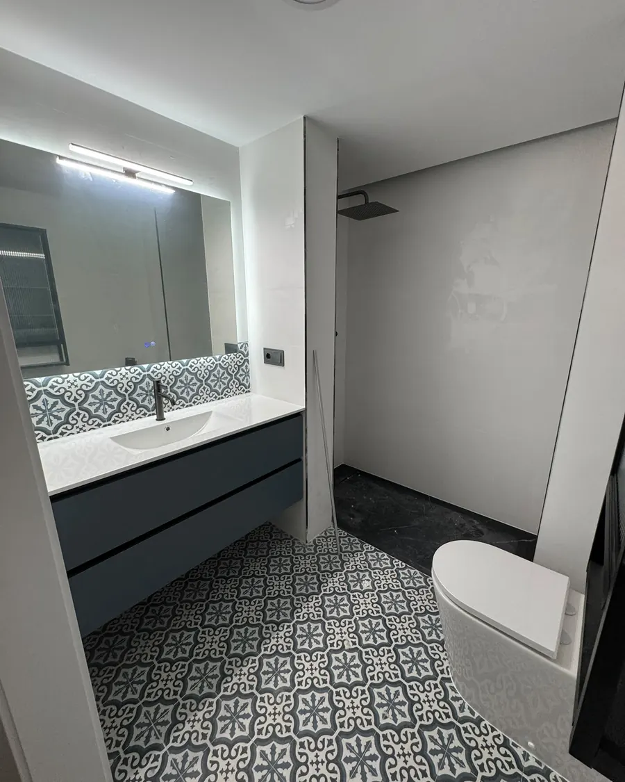 Baño con suelo de baldosa hidráulica y mueble azul