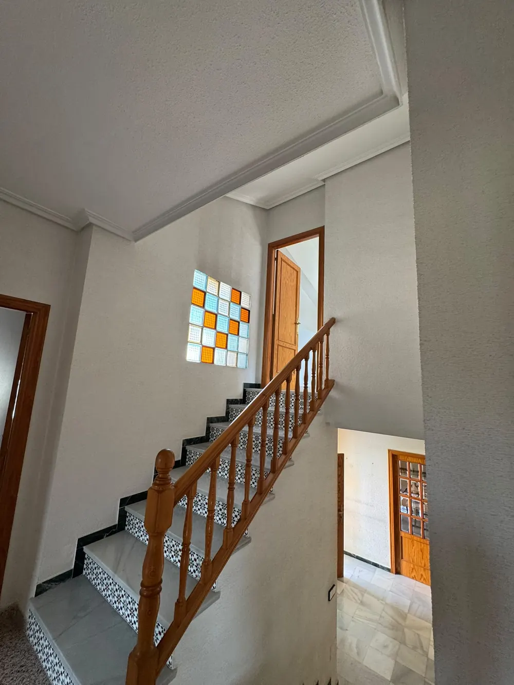 La escalera antes de la reforma, con barandilla de madera y peldaños de azulejo