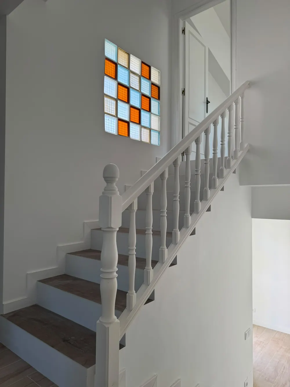 Escalera reformada con paredes lisas blancas, barandilla blanca y peldaños nuevos