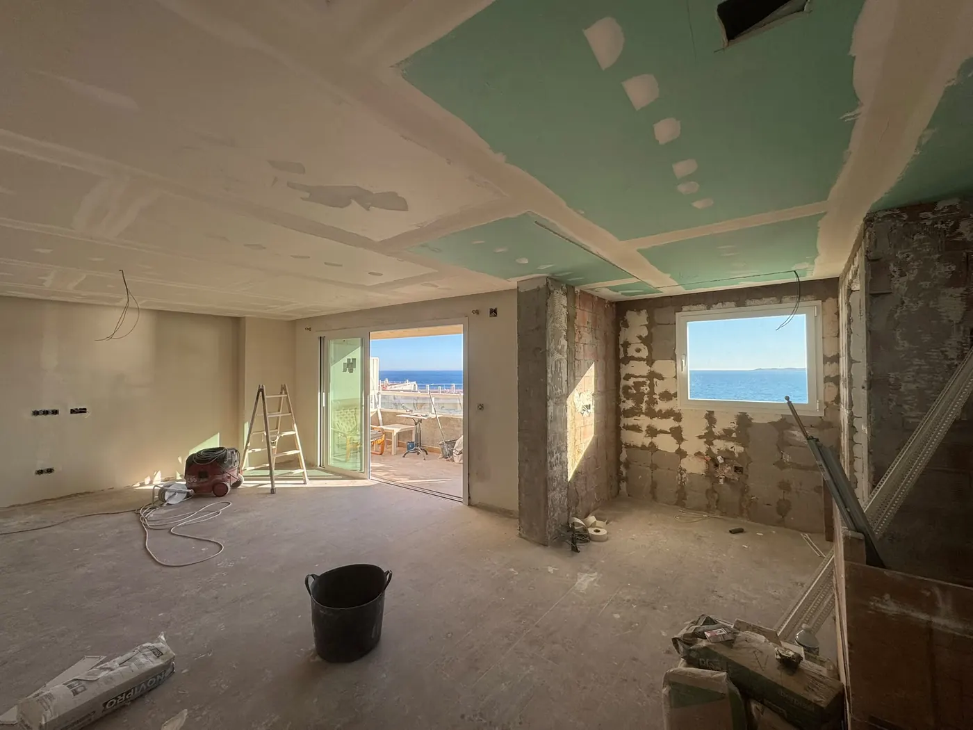Salón en obra, con el techo de pladur instalado y las paredes todavía sin terminar